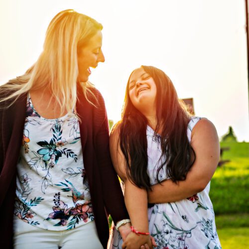 A Portrait of trisomie 21 adult girl smilin outside at sunset with family friend Special Needs Planning