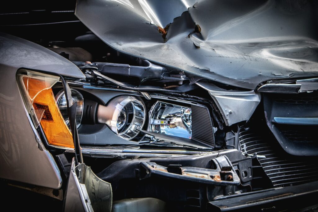 Close-up of a crashed car's headlights and front bumper, scratched, bent, and totaled.